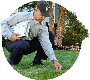 Lawn Doctor expert with clipboard stoops down to provide Lawn Service in Corrales