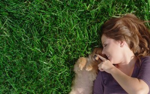 Pretty Woman playing with cute puppy on manicured green grass after our professional lawn care in Altoona