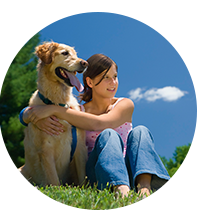 Girl sitting and hugging her dog on grass treated with lawn pest control services