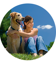 Girl sitting and hugging her dog with lawn care trees in background