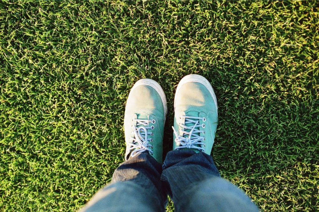 Camera staring down at shoes on freshly manicured grass by Lawn Doctor of Cypress