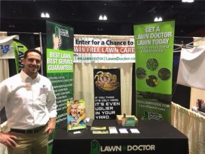 Owner of Manchester lawn doctor in front of booth