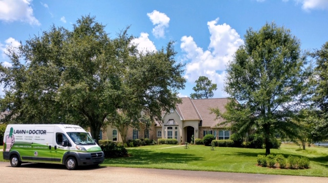 lawn doctor van in front of large house with beautiful yard showing lawn care in Mandeville