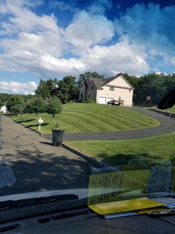 Beautiful blue sky over a freshly manicured lawn flanking a driveway showing lawn care services in Rockland County