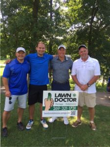 four guys standing in front of lawn doctor sign