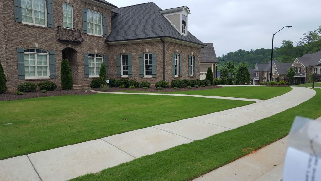 Very green lawn in front of large house showing affordable lawn care in Raleigh