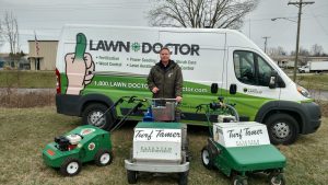 Owner with his lawn aeration equipment and van