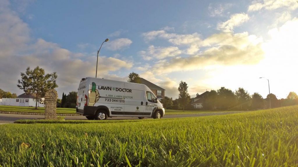 lawn doctor truck on a front lawn in the sunset