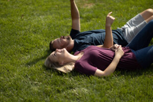 A couple lying on healthy Green Grass of a Lawn
